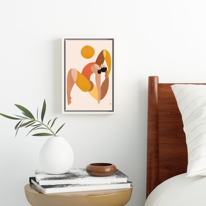 colorful print of person doing yoga pose above gold side table