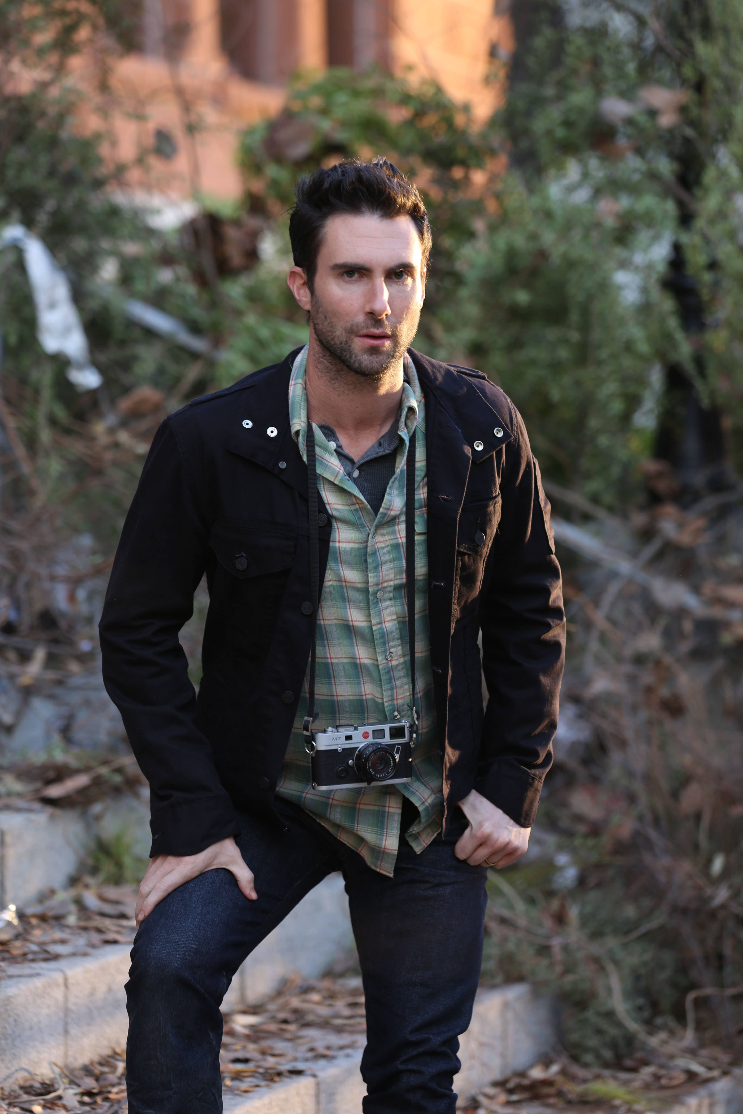 Adam Levine as the tourist, standing outside the decrepit asylum