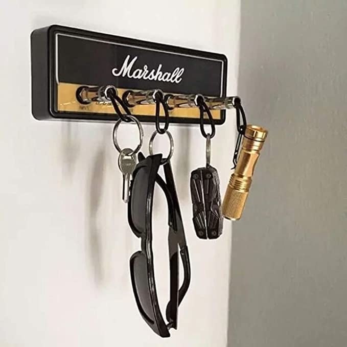 A set of keys, sunglasses, and a flashlight plugged into the key holder while it is mounted on a wall