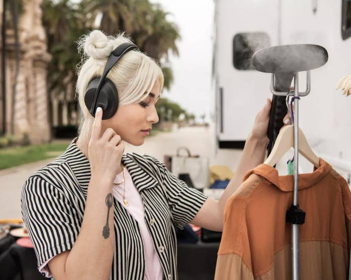 a person adjusting the volume by tapping the side of their headphones