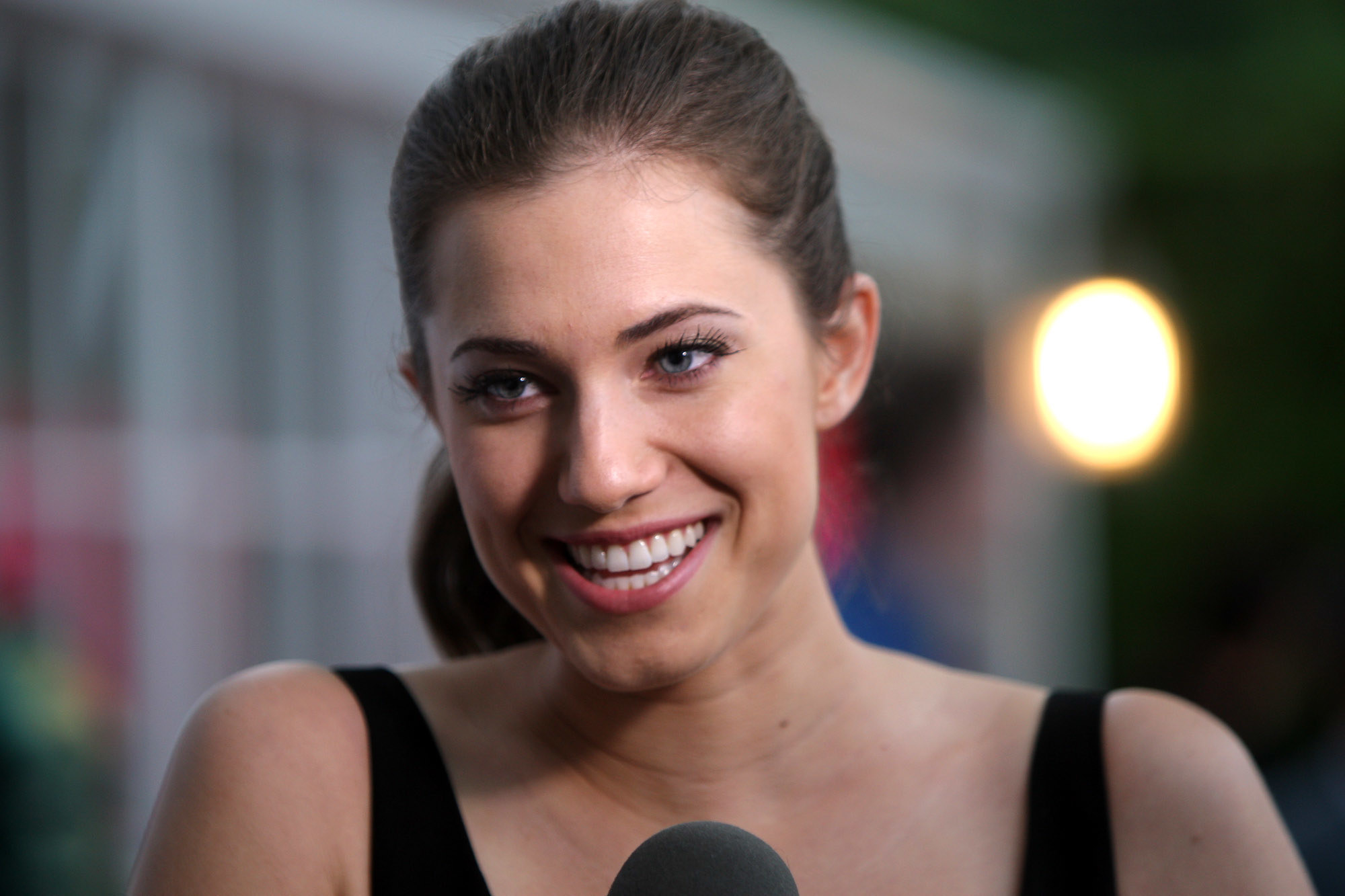 Allison Williams in a ponytail laughing in an interview at a film festival