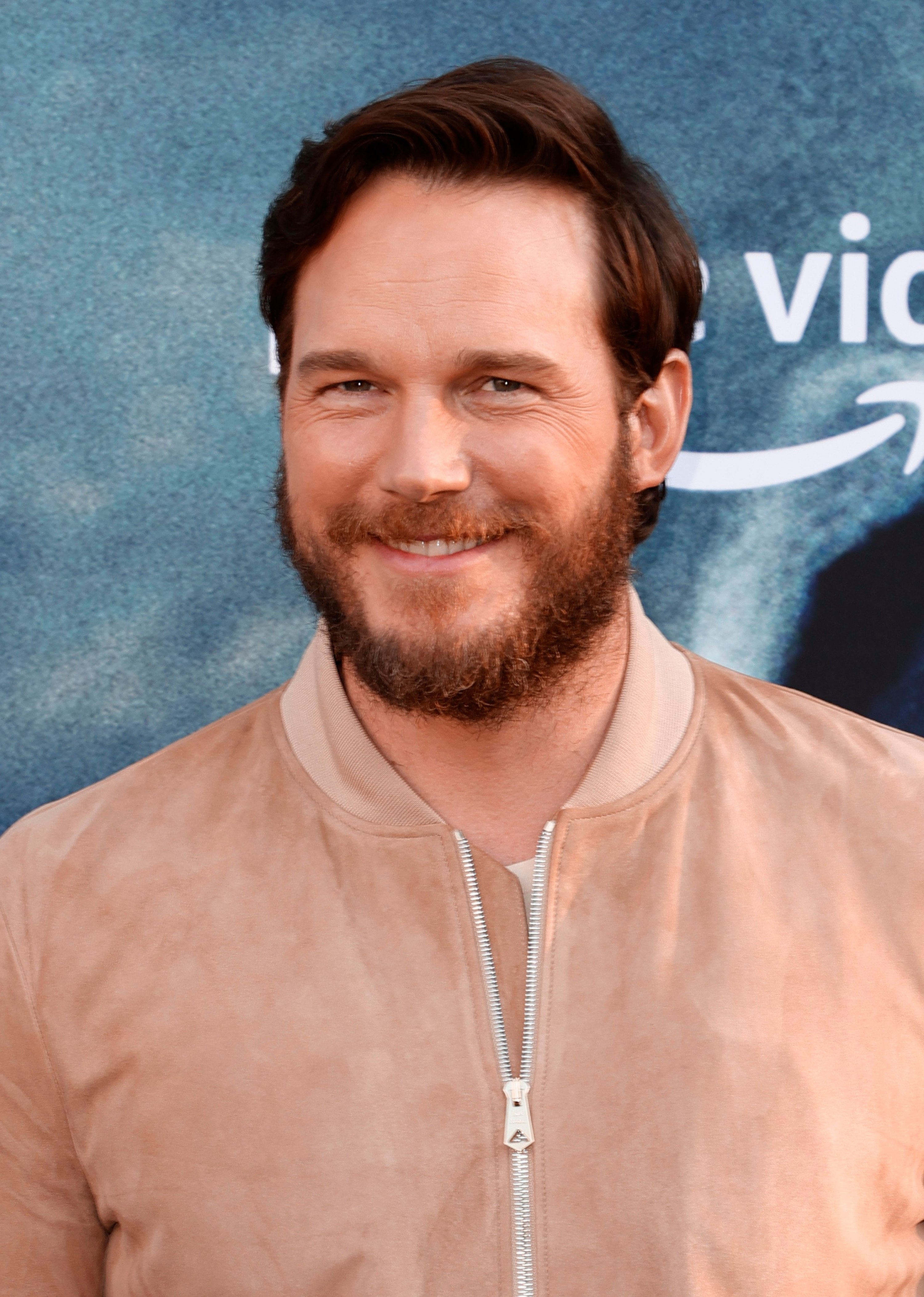 Chris Pratt at a premiere in a zip-up jacket smiling in 2021