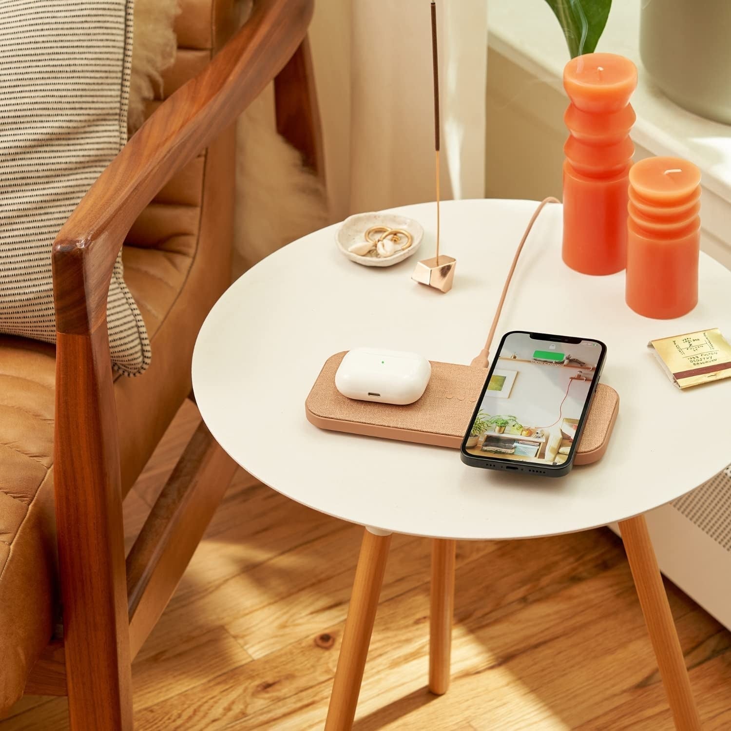 an iPhone and AirPod case sitting on the tan charging station
