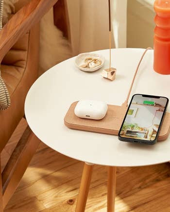 an iPhone and AirPod case sitting on the tan charging station
