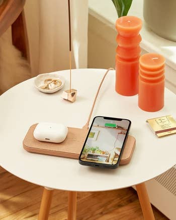an iPhone and AirPod case sitting on the tan charging station