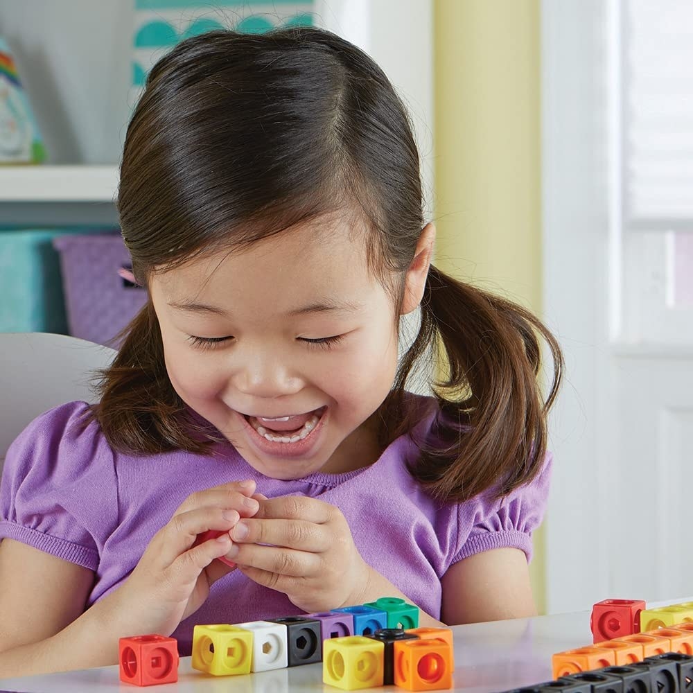 a smiling child playing with the rainbow cubes