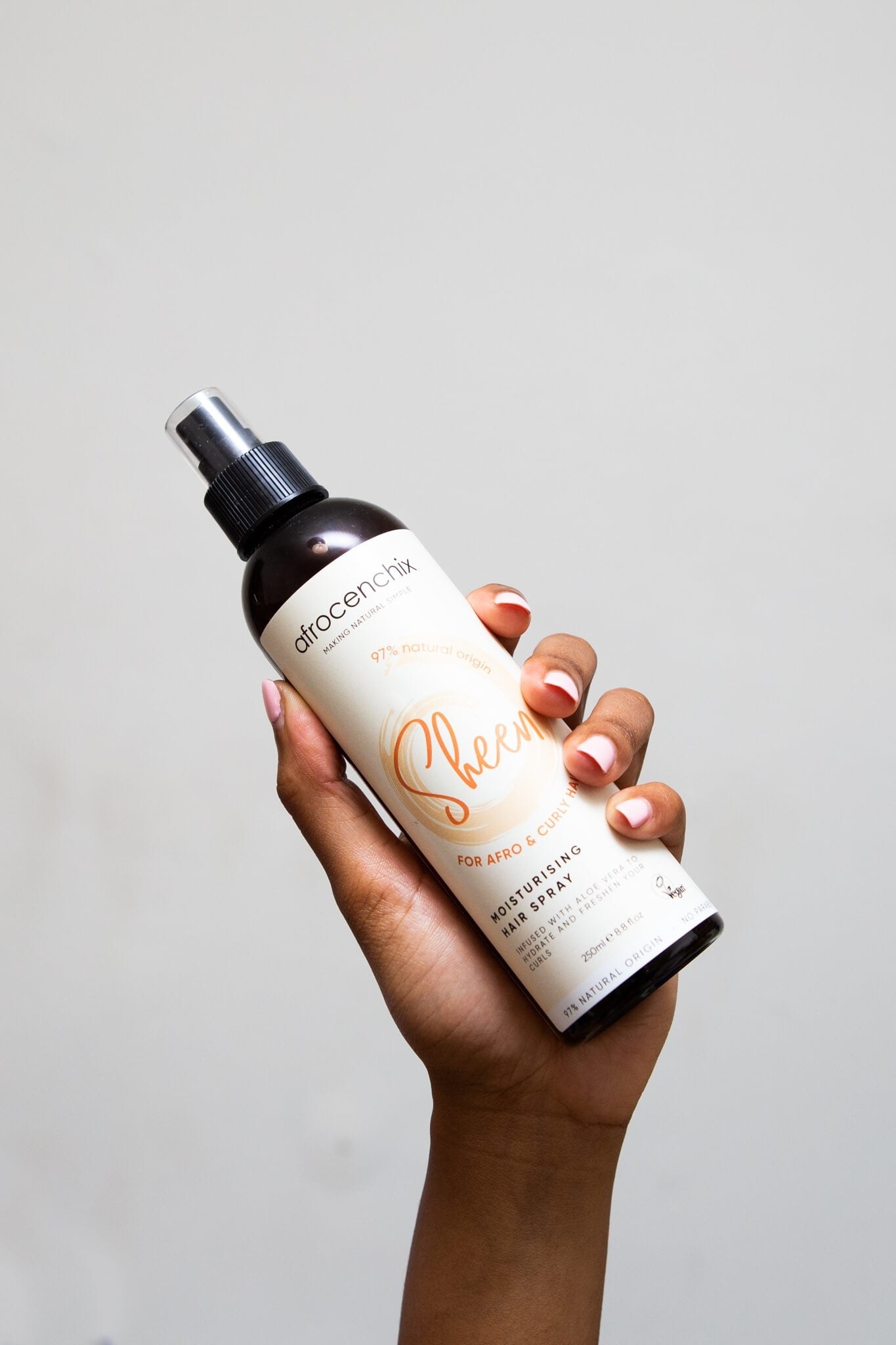 A hand model holds up a bottle of moisturising hair spray.