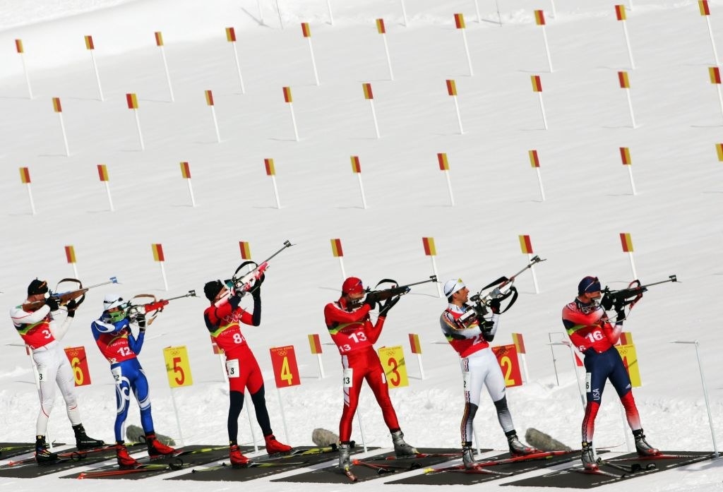 a line of male athletes fire at their targets
