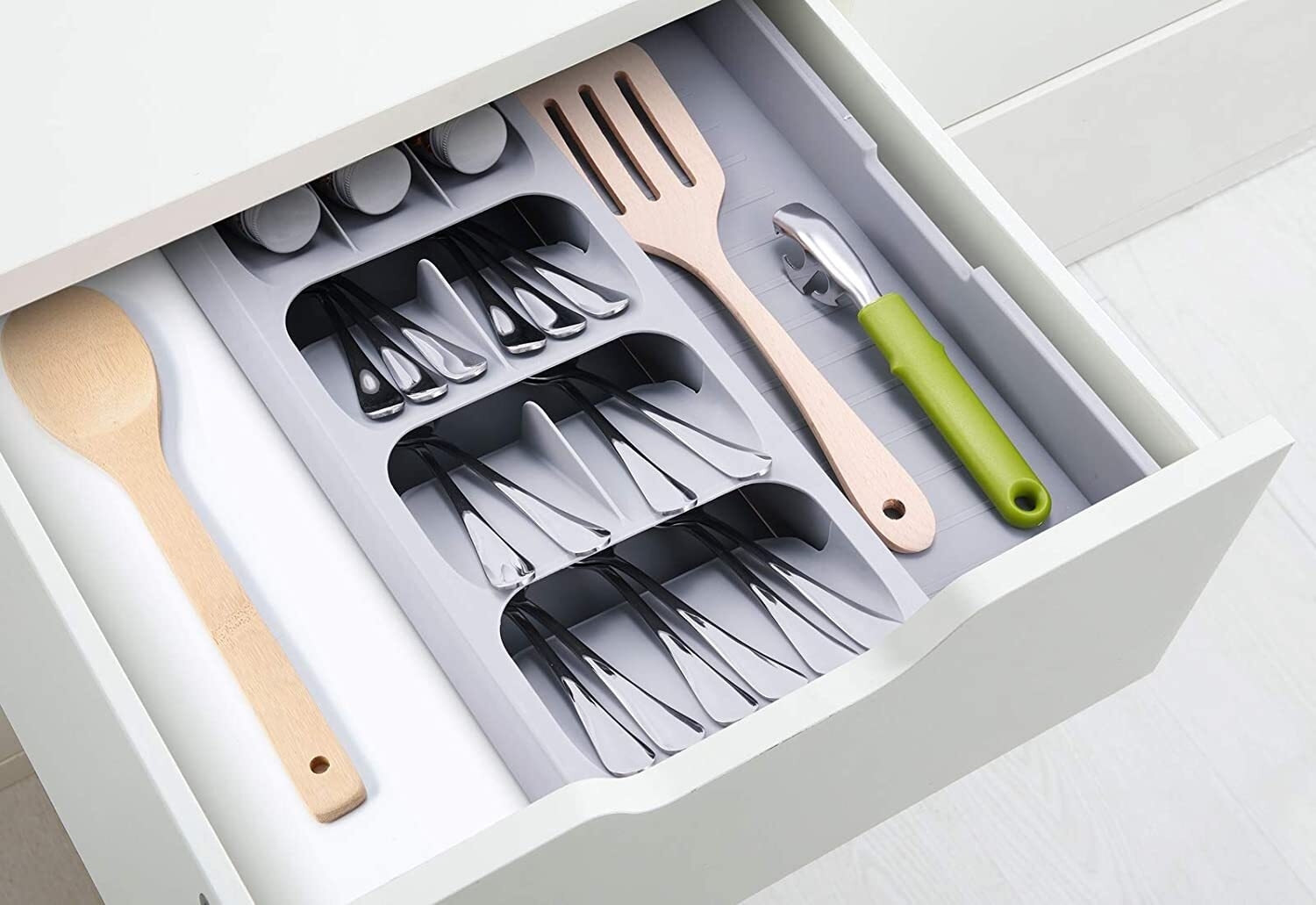 The drawer organizer in a drawer holding both eating utensils, and cooking utensils