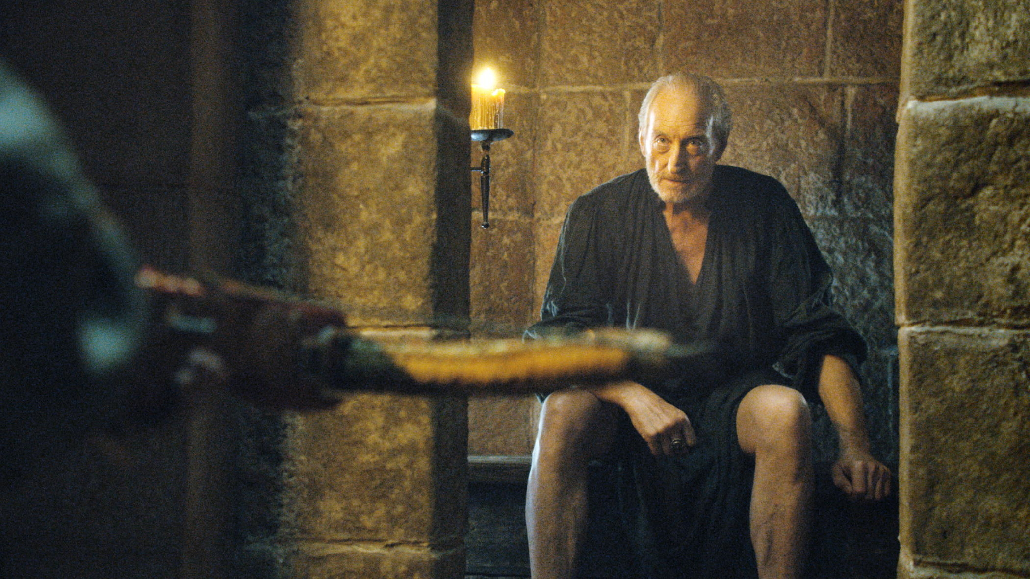 Charles Dance as Tywin Lannister sitting on the toilet with a crossbow pointing at him