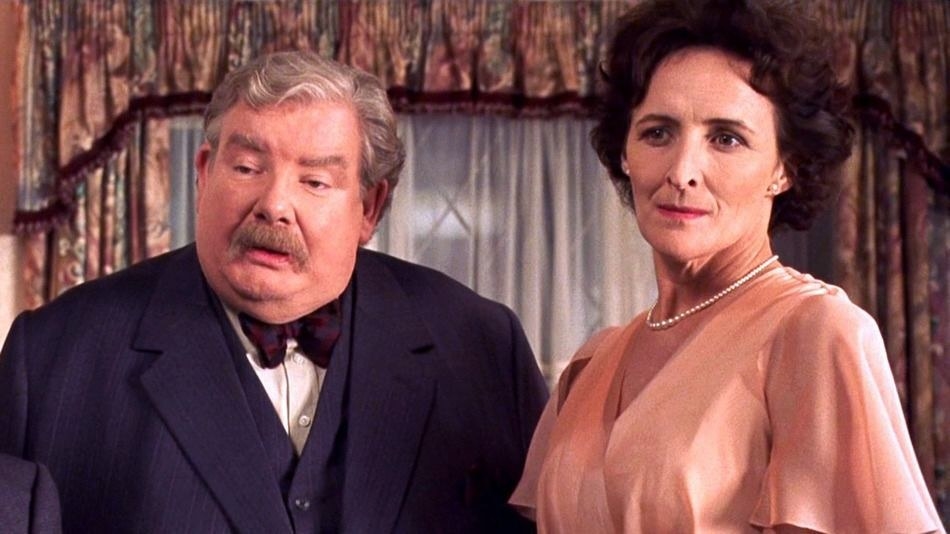 vernon and petunia dursley wear a suit and a v-neck dress, respectively