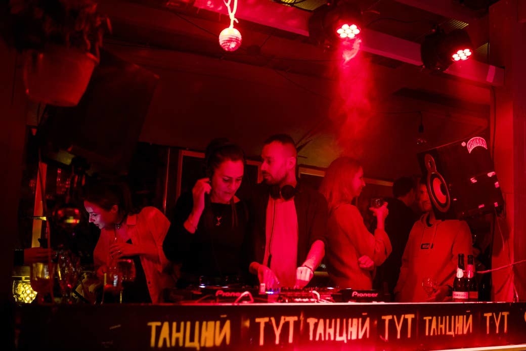 DJs play a set amid red lighting at Gnezdo Bar in Kyiv
