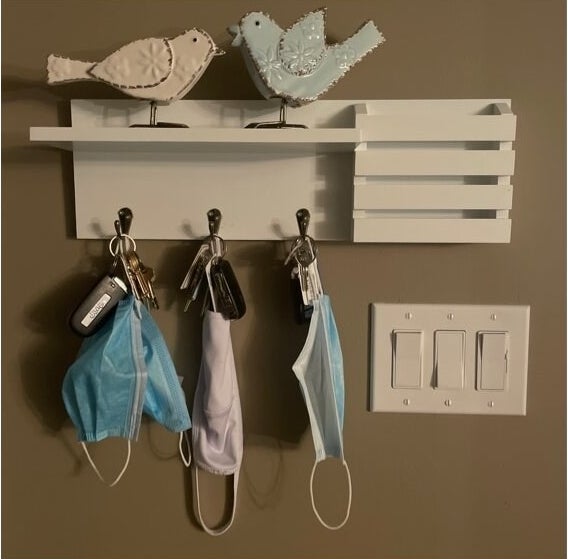 A reviewer&#x27;s image of a utility shelf with pocket and hanging hooks mounted onto a wall