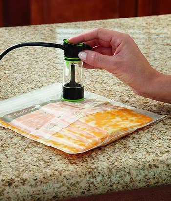 a food vacuum sealer being used to suck excess air out of a bag with food inside
