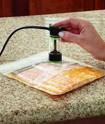 a food vacuum sealer being used to suck excess air out of a bag with food inside