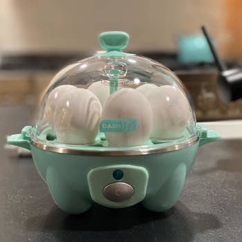 a reviewer photo of the egg cooker in blue with six eggs inside