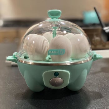 a reviewer photo of the egg cooker in blue with six eggs inside