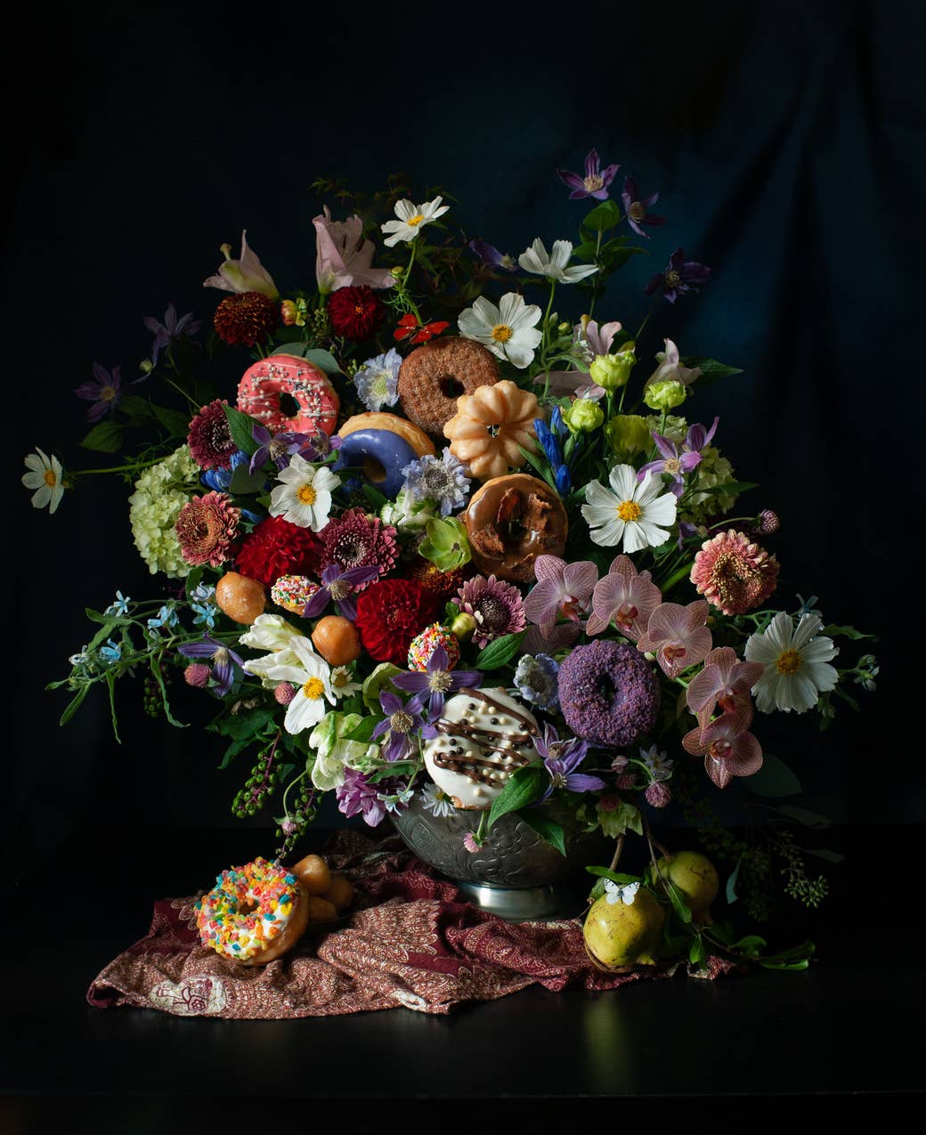 A large bouquet showing some flowers and an assortment of donuts