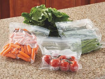 multiple vacuum zipper bags with various small veggies stored inside, the excess air visibly sucked away