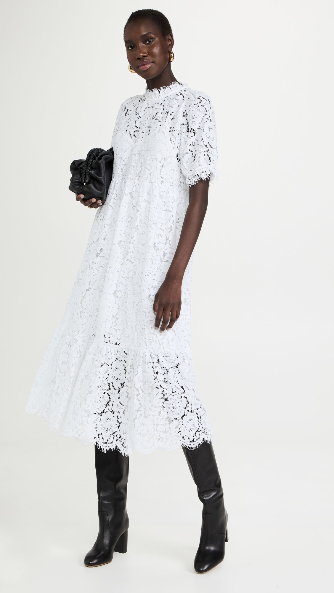 A model wearing the white lace dress with black boots and a black bag
