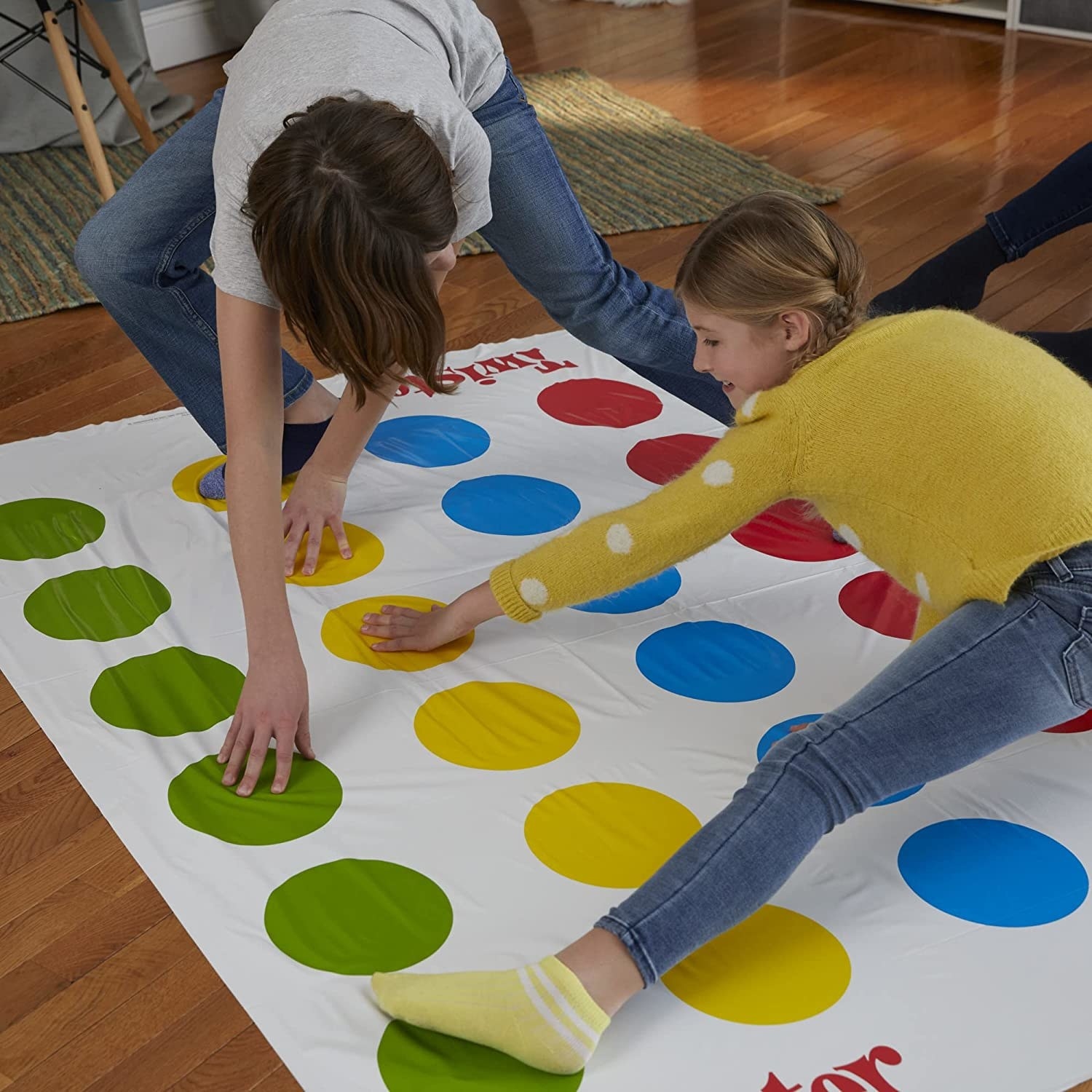 Two people play a game of Twister in a living room