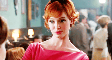 Joan Holloway looks someone up and down with an unamused expression on her face on Mad Men