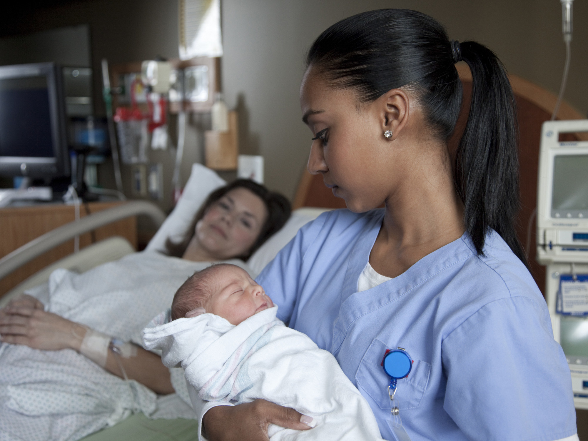A nurse holds a baby in a hospital