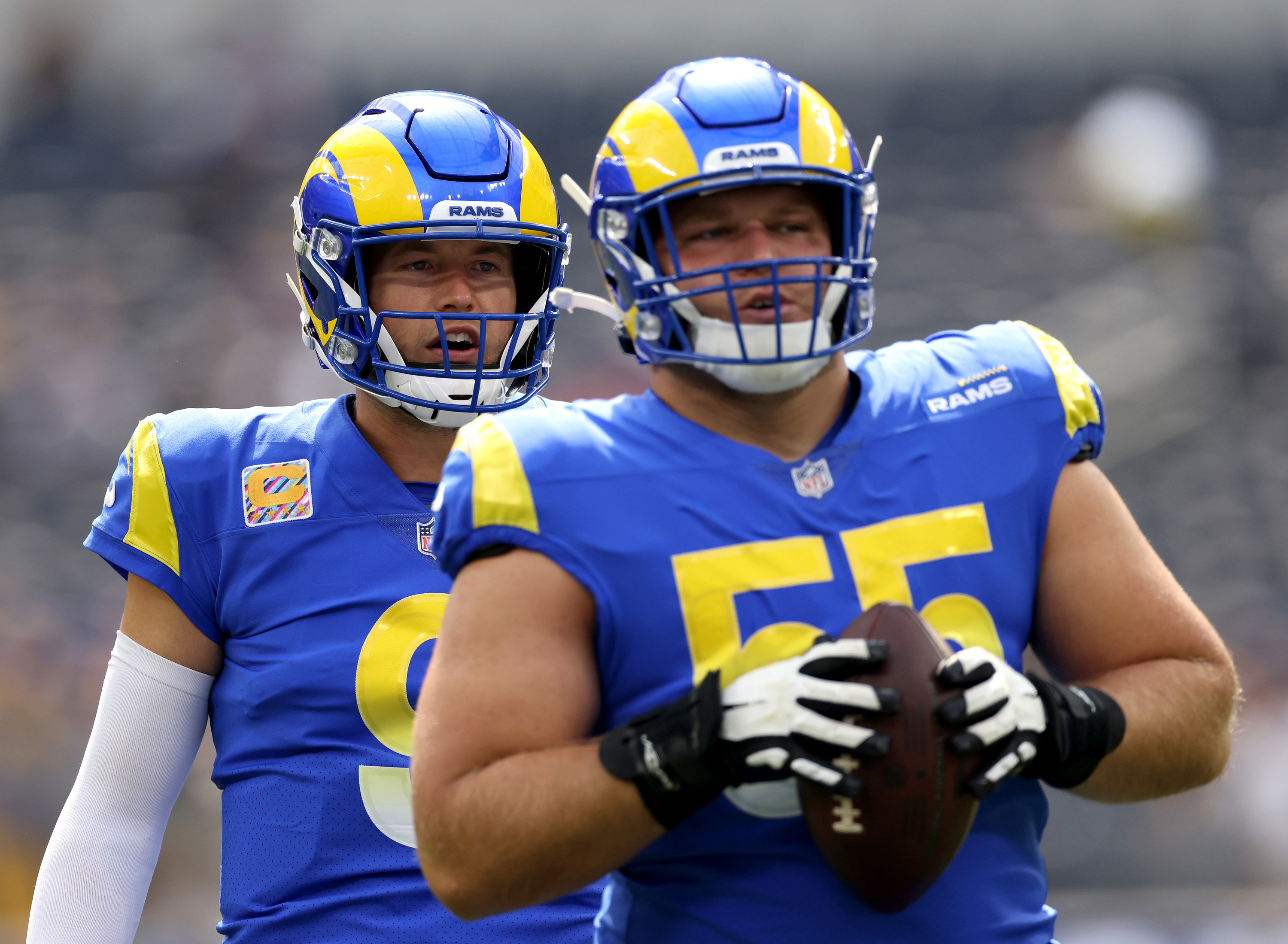 Brian Allen holds a football while Matt Stafford stands behind him