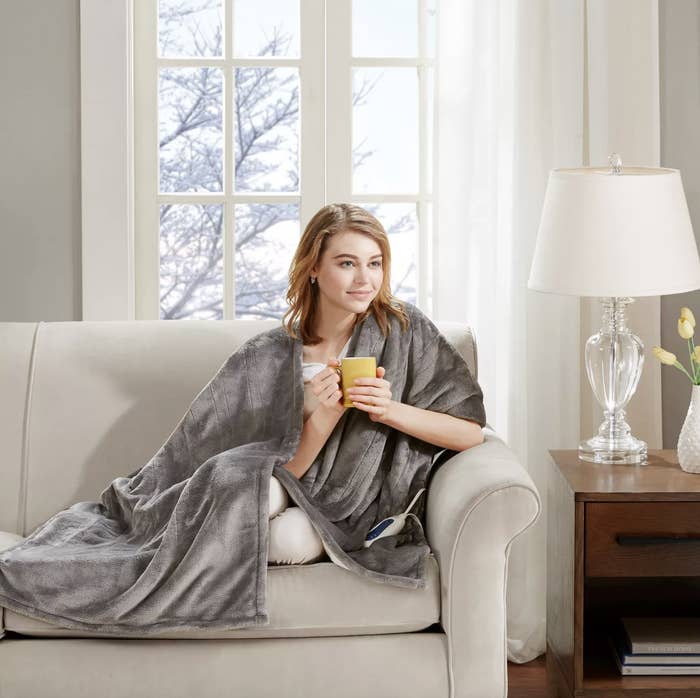 a model wearing the blanket and holding a mug