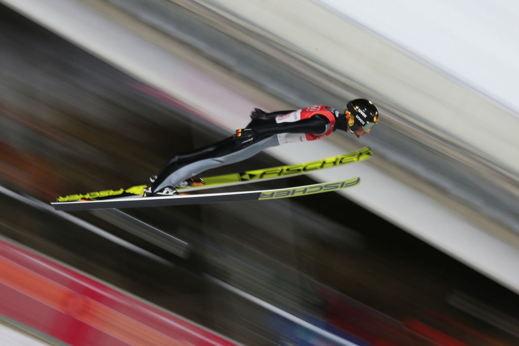 a ski jumper leans forward to make a jump