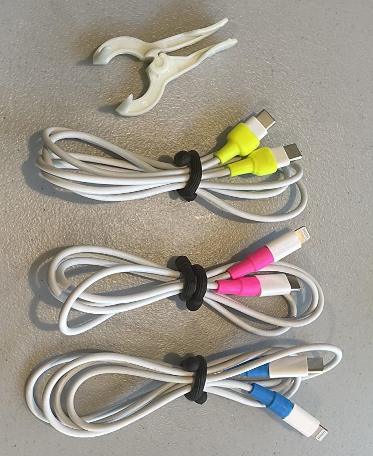 a reviewer photo of three different charging cords with the cord protectors installed on each end sitting next to the included applicator tool