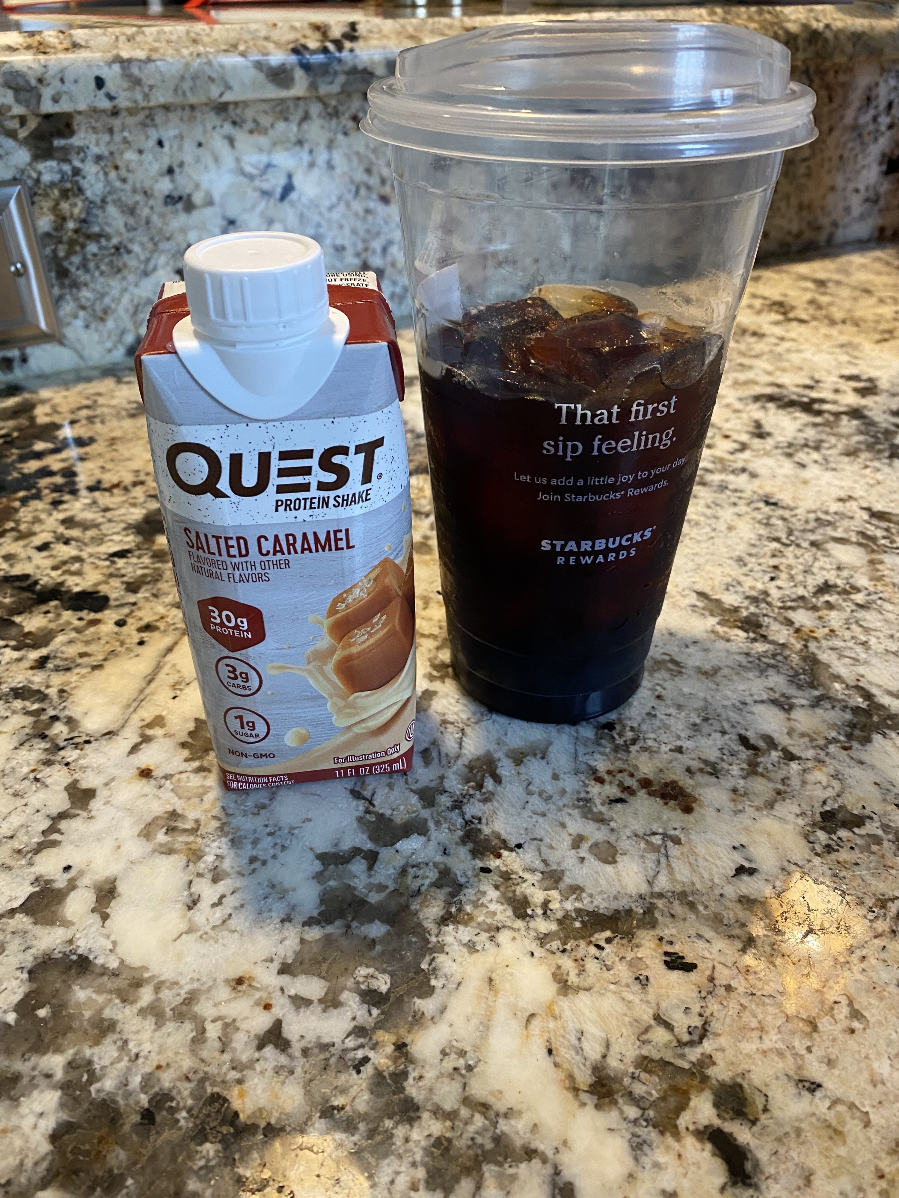A large iced coffee next to a Quest protein sake on a counter