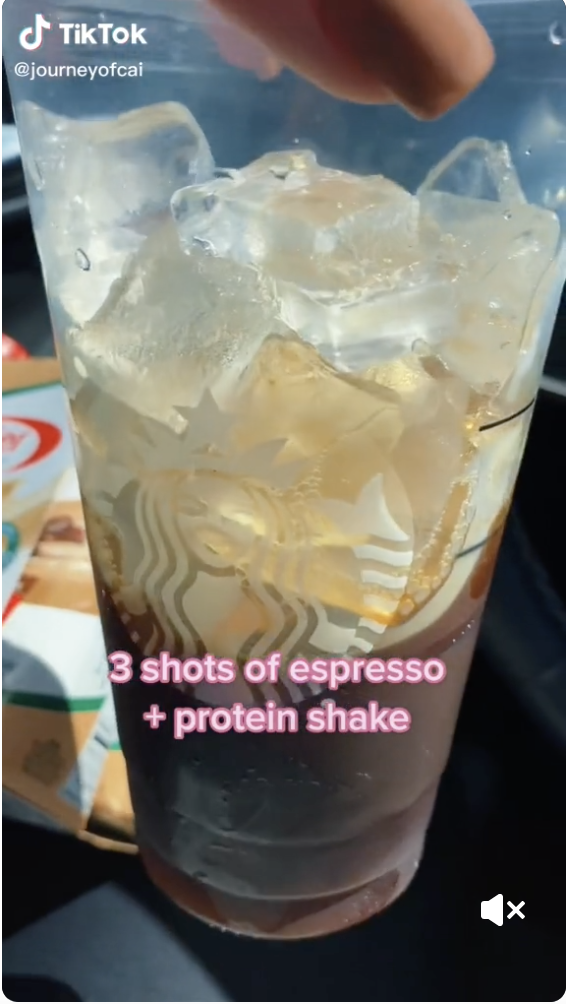 A Starbucks cup with coffee in it ad text that reads, &quot;3 shots of espresso + protein shake&quot;