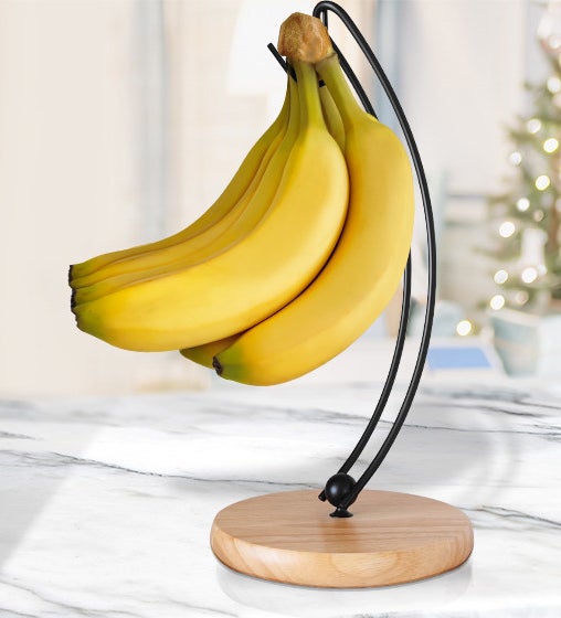 banana bunch hanging on a banana stand with a black hanger and wooden base