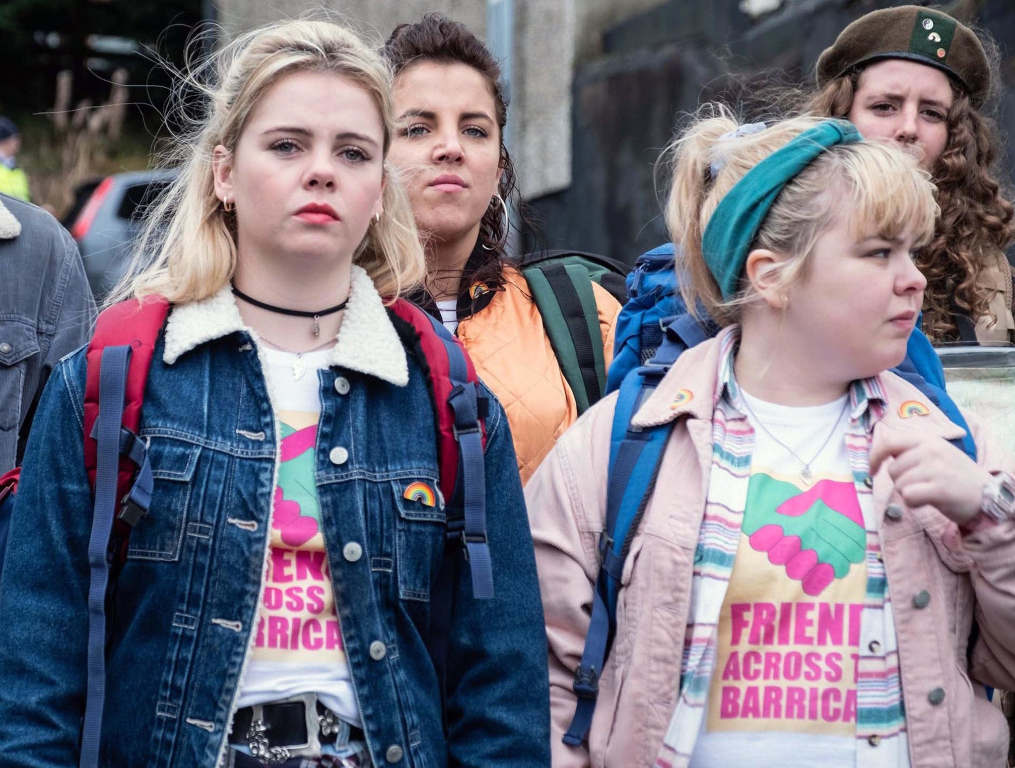 Two blonde teen girls with backpacks leading group of friends