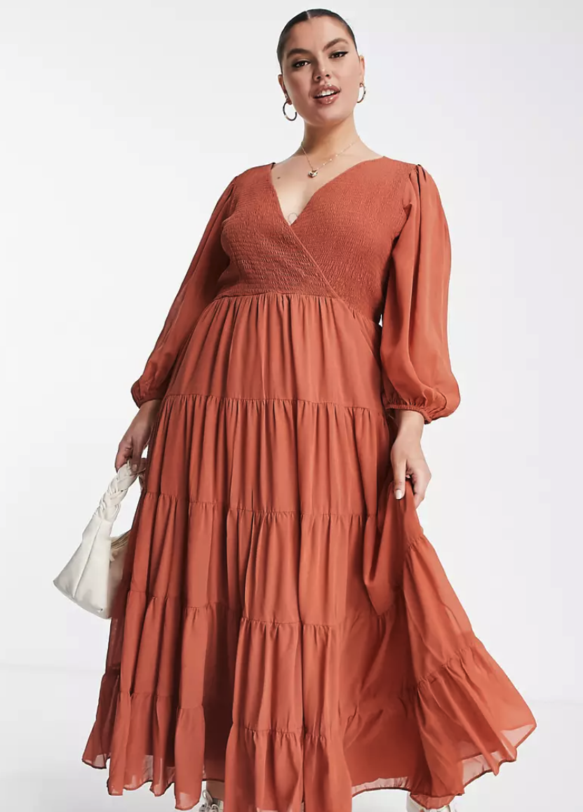a model wearing the rust-colored dress with a tiered hem and ruched top.