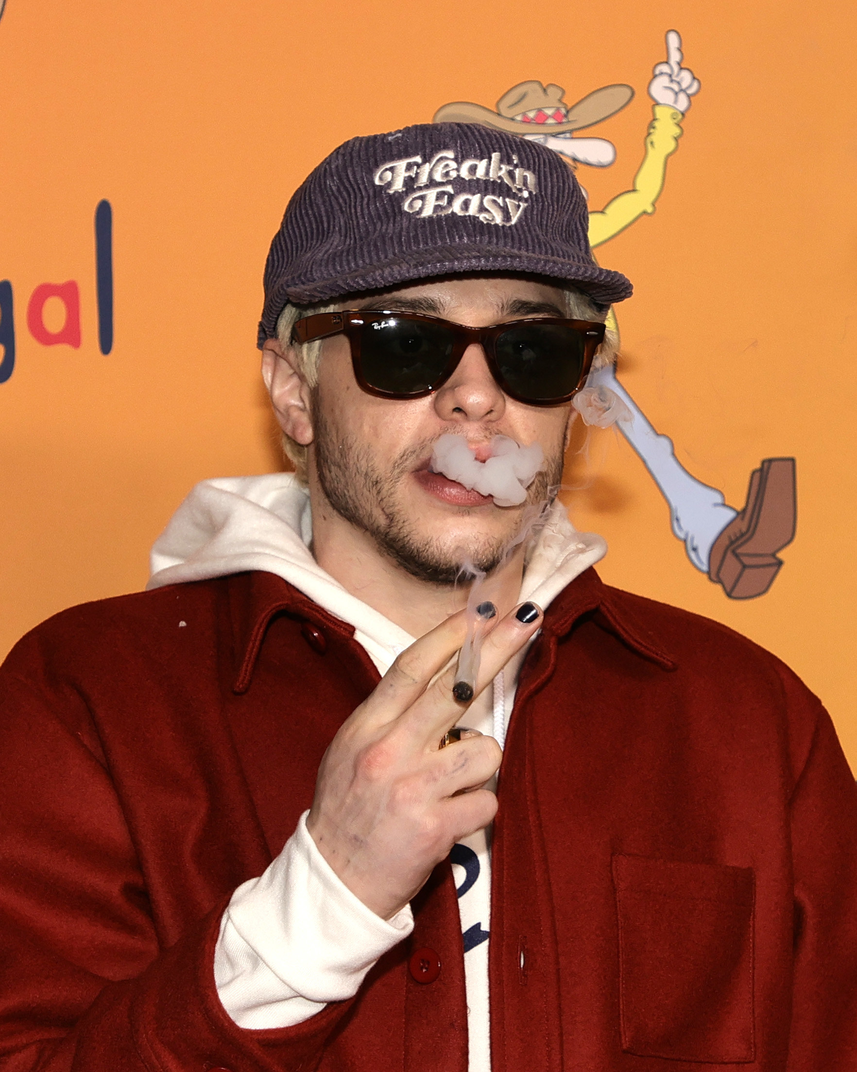 Pete Davidson smokes at an event