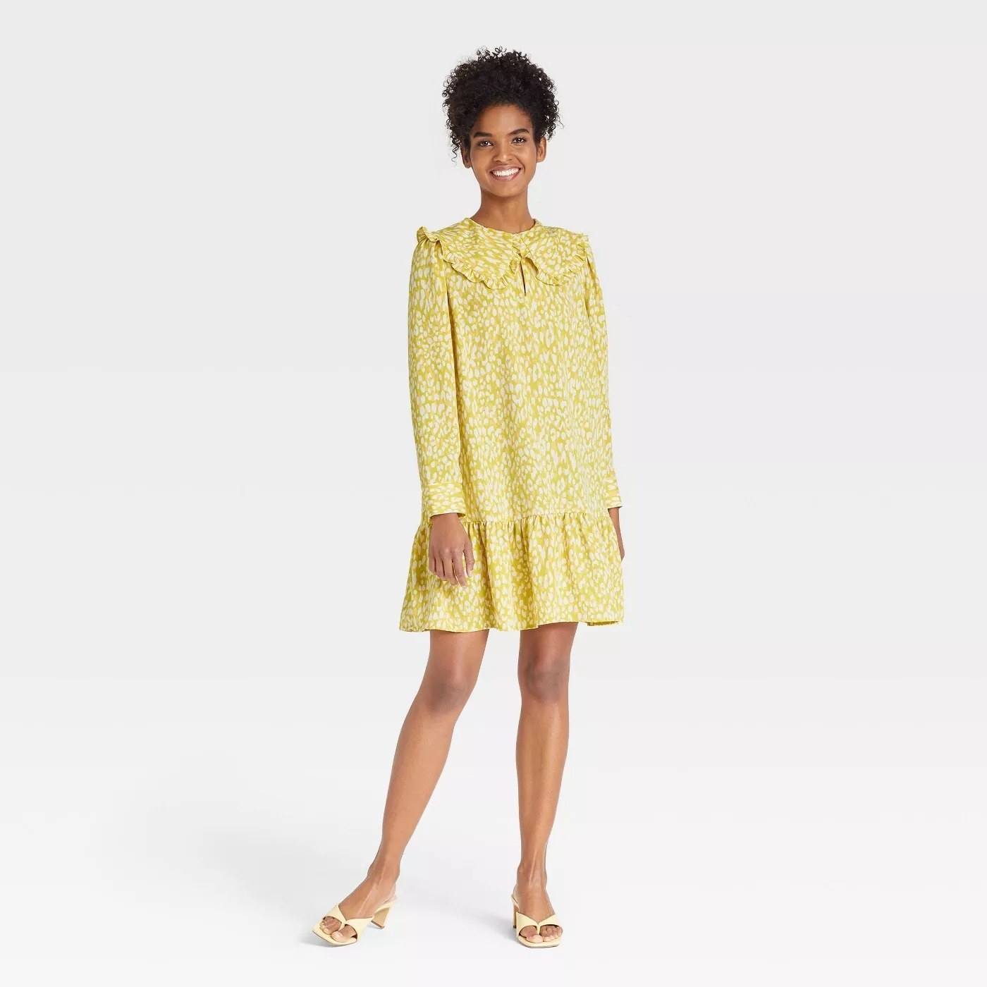 Model wearing yellow patterned dress, stops above the knee