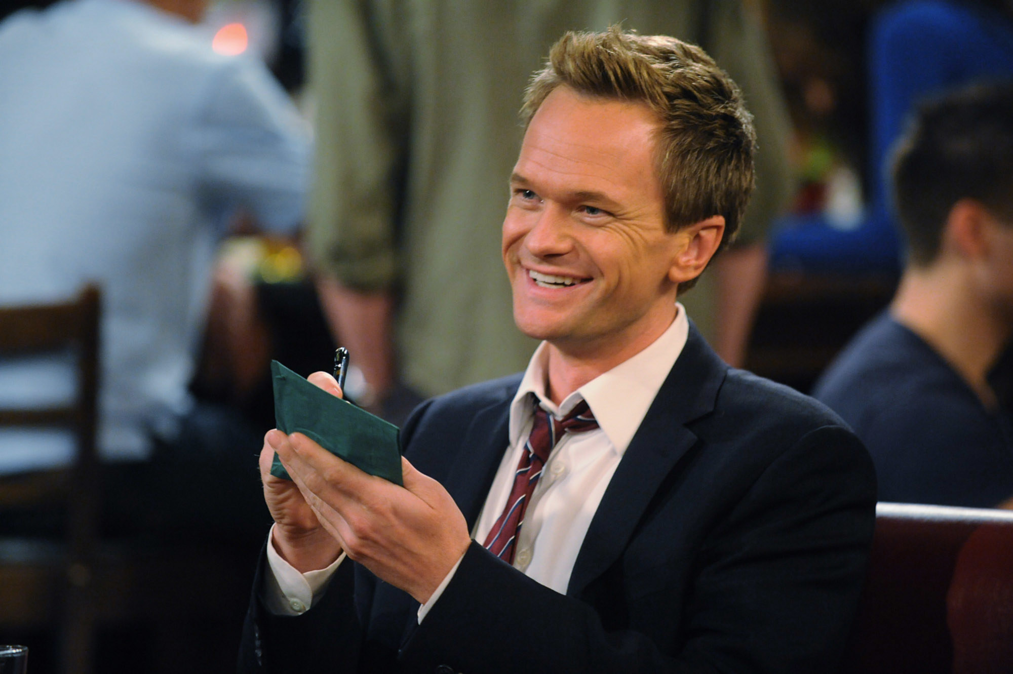 Barney sits in a bar and holds out a checkbook to write in