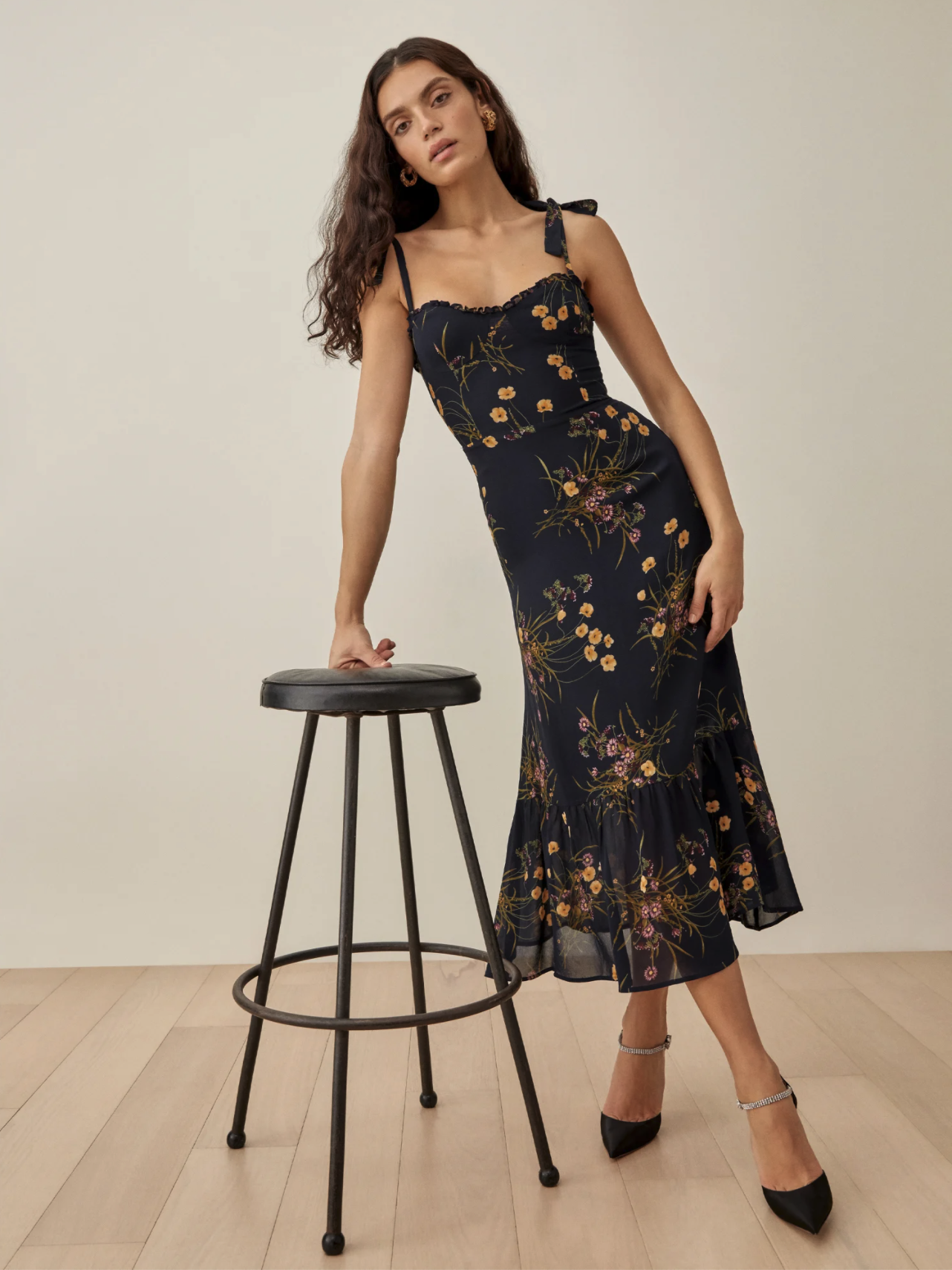 a model wearing a black dress with yellow and purple floral scattered about