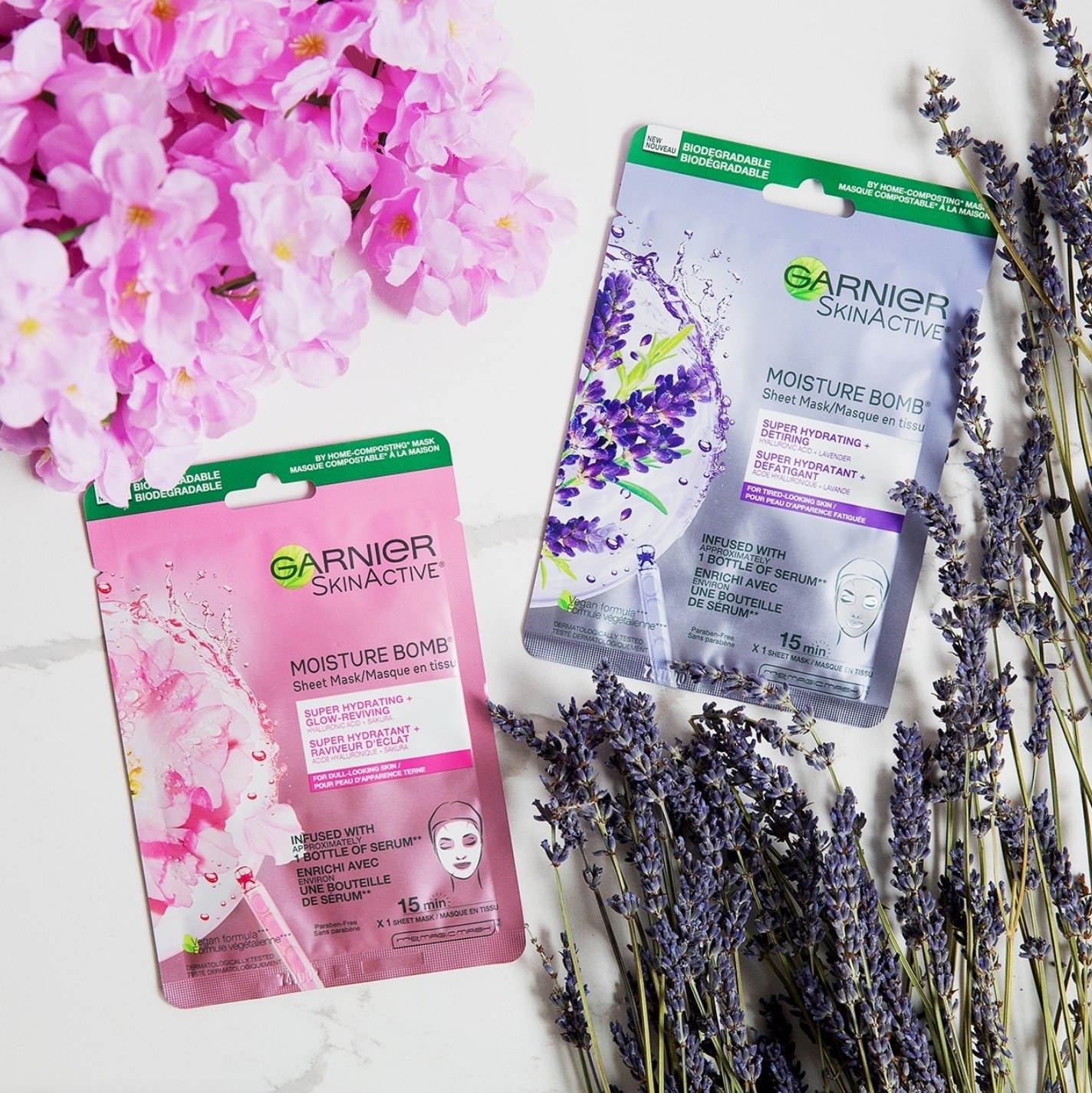 A pair sheet masks laying on a marble table surrounded by fresh lavender and cherry blossoms