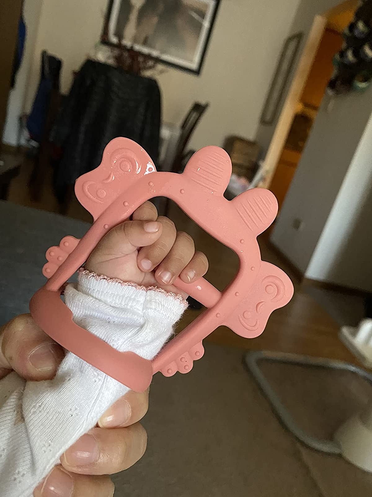 a baby wearing the pink teether and gripping the handle