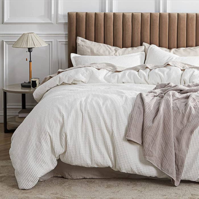 The bedding on a bed with a velour headboard