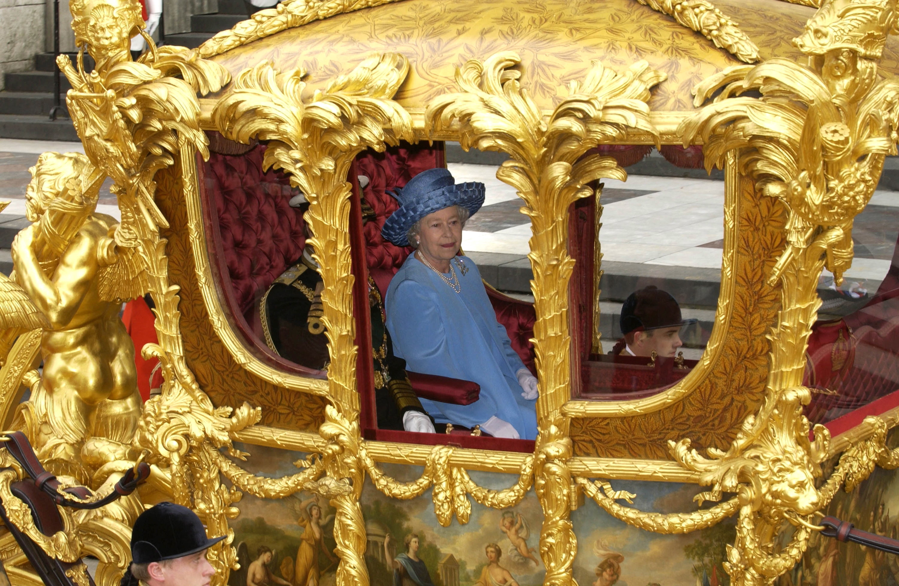 Queen Elizabeth II in a blue suit in a carriage 