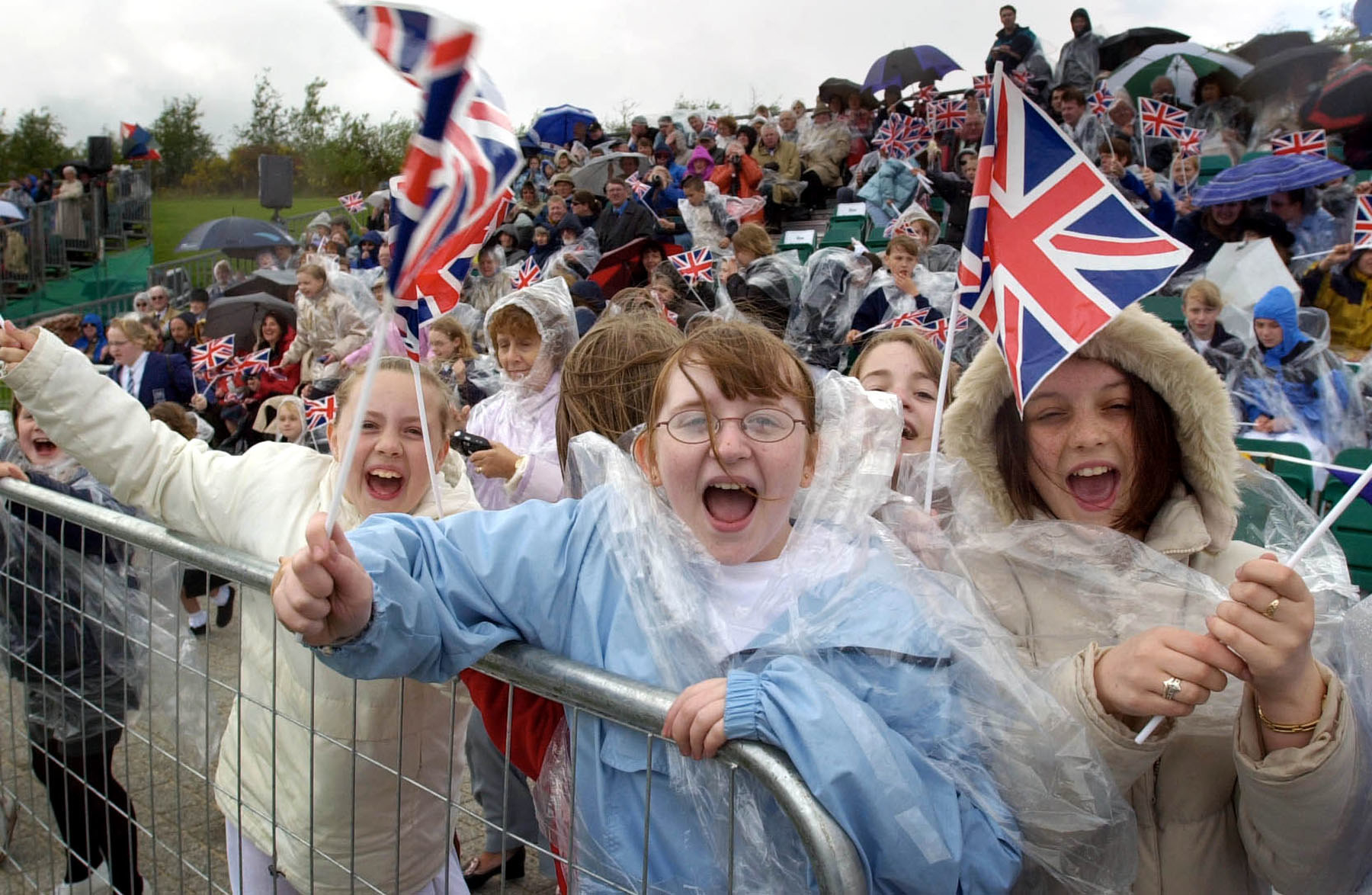 a group of people waving and wavign flafs at the queens jubilee