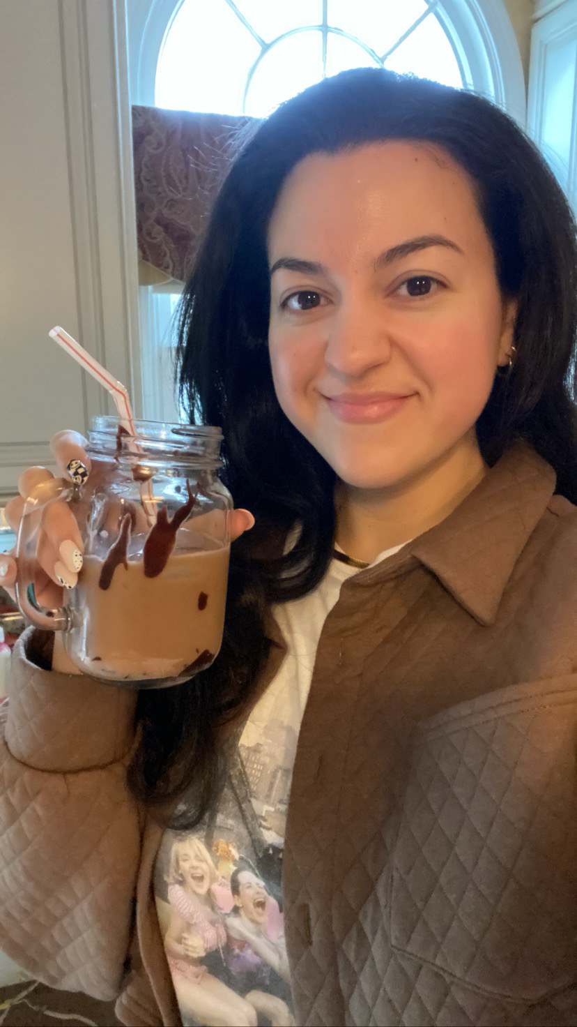 The author taking a selfie holding up a glass filled with a chocolate protein coffee drink