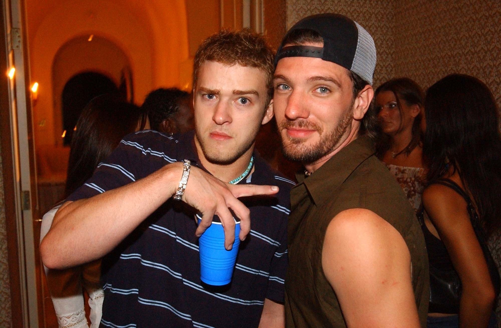 Justin standing next to JC at party while pointing at him and holding a Solo cup