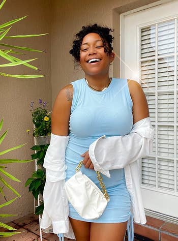 a reviewer posing in the baby blue dress with a white top and matching purse