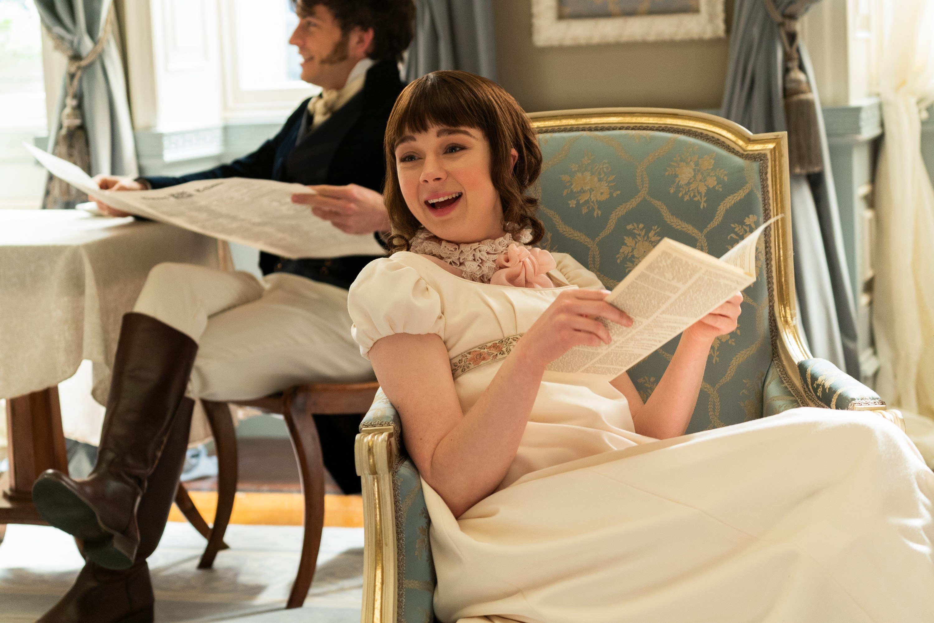 Teen girl with bangs reading a pamphlet in a chair and smiling