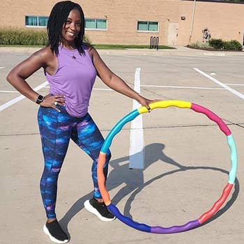 reviewer wearing the galaxy print leggings while holding an exercise hoop